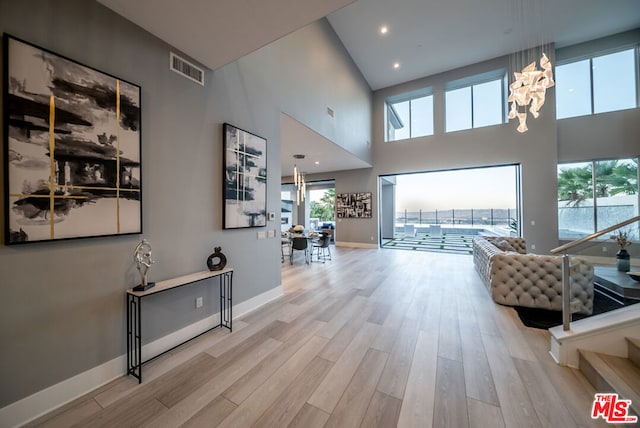 corridor featuring a wealth of natural light, light hardwood / wood-style flooring, and a high ceiling