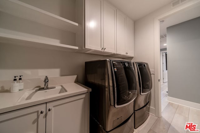 laundry room with cabinets, washer and clothes dryer, and sink