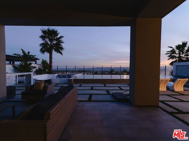 patio terrace at dusk featuring an outdoor living space and a water view