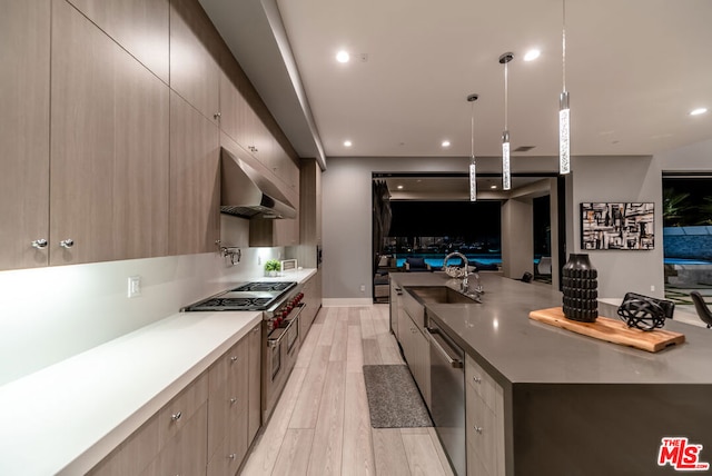 kitchen featuring light brown cabinets, sink, appliances with stainless steel finishes, decorative light fixtures, and light hardwood / wood-style floors