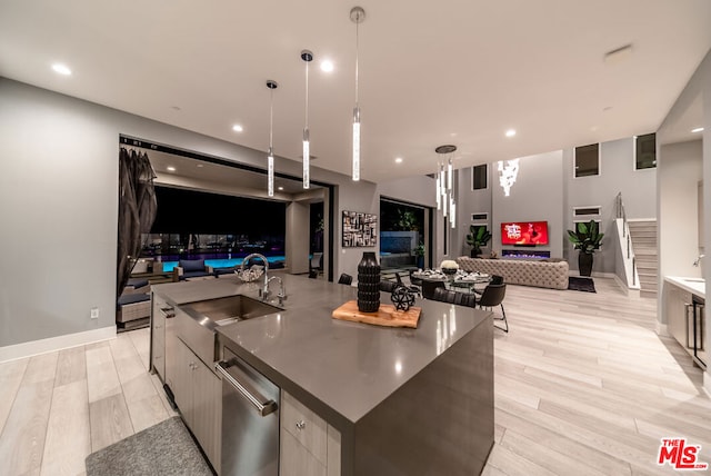 kitchen featuring sink, hanging light fixtures, stainless steel dishwasher, a large island, and light hardwood / wood-style floors