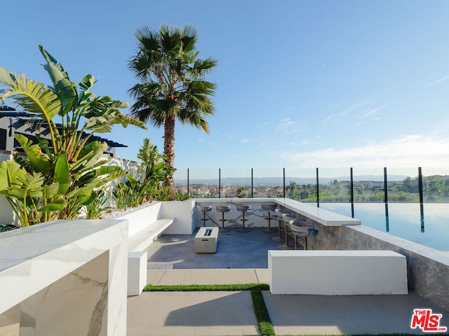 view of swimming pool featuring exterior bar, a patio, and a water view