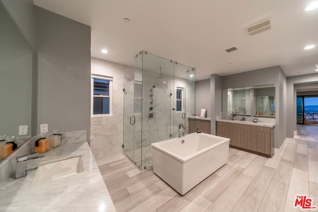 bathroom with wood-type flooring, vanity, and independent shower and bath