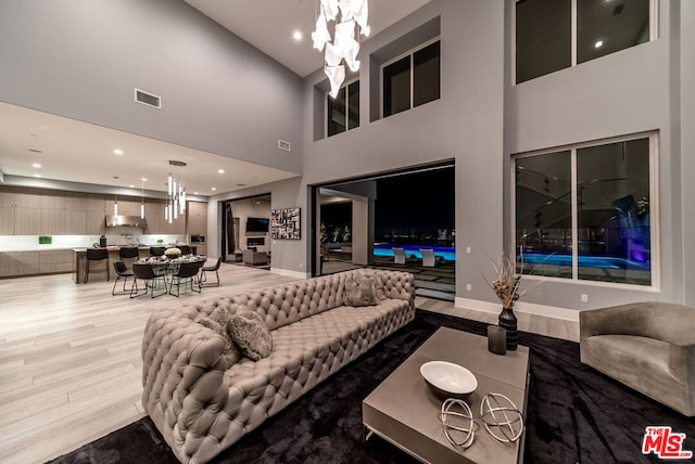 living room featuring a high ceiling, hardwood / wood-style flooring, and an inviting chandelier