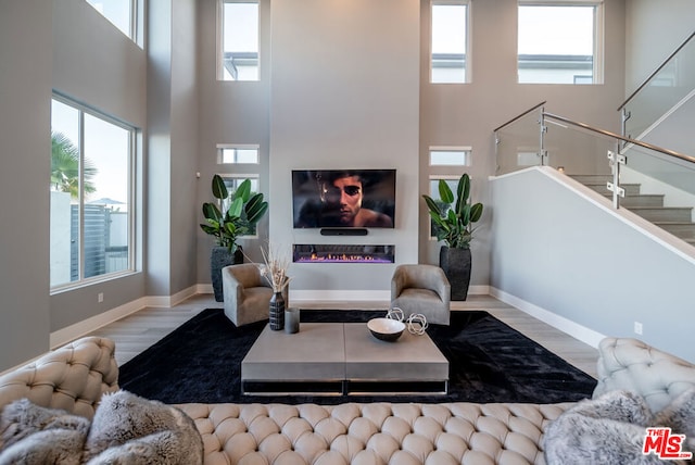 living room with light wood-type flooring and a towering ceiling