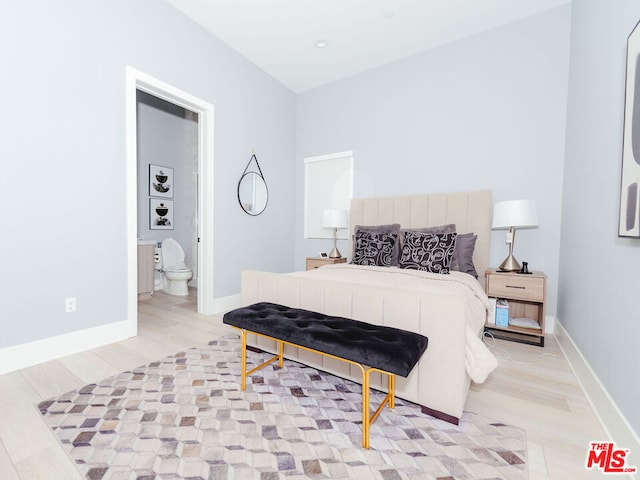 bedroom featuring connected bathroom and light hardwood / wood-style floors