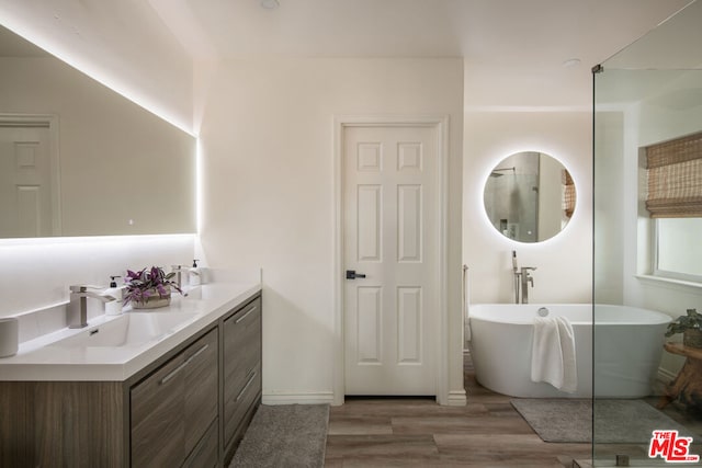 bathroom with vanity, wood-type flooring, and a tub to relax in