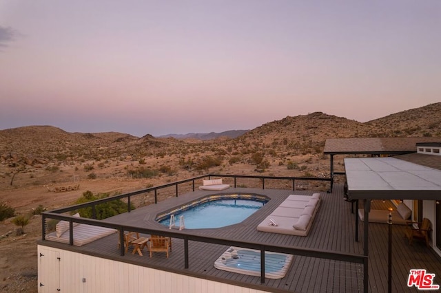 pool at dusk featuring a hot tub, a mountain view, and a gazebo