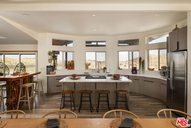 kitchen featuring a wealth of natural light, stainless steel fridge, light hardwood / wood-style flooring, and a breakfast bar area