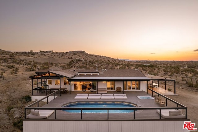 back house at dusk featuring a patio and a mountain view