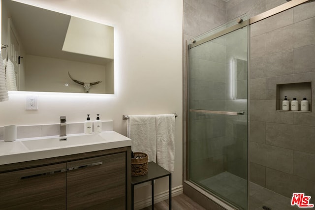 bathroom featuring vanity, wood-type flooring, and a shower with door