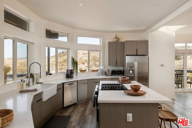 kitchen with sink, stainless steel appliances, a kitchen island, and dark hardwood / wood-style flooring