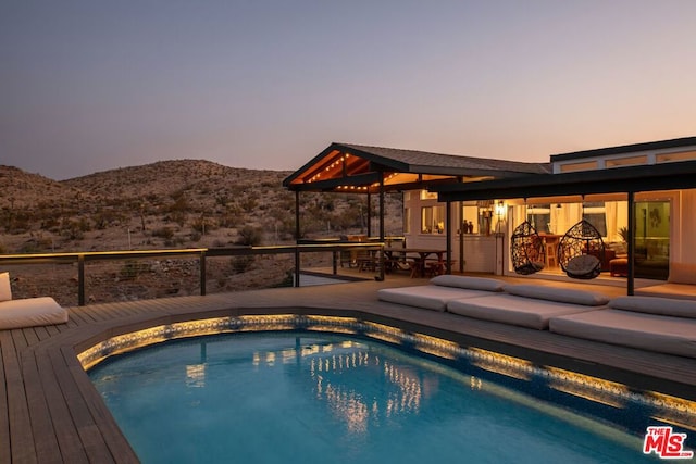 pool at dusk featuring a patio area and a mountain view