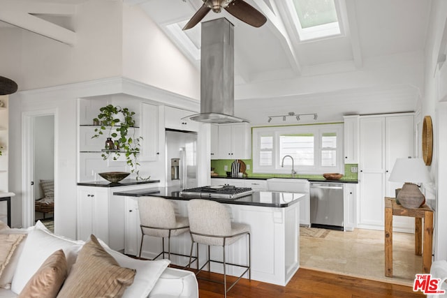 kitchen featuring island range hood, stainless steel appliances, a breakfast bar, and white cabinets