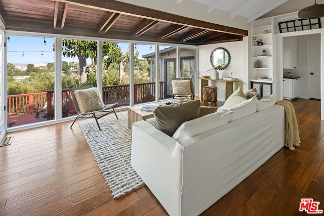 living room with built in shelves, wood-type flooring, and vaulted ceiling with beams