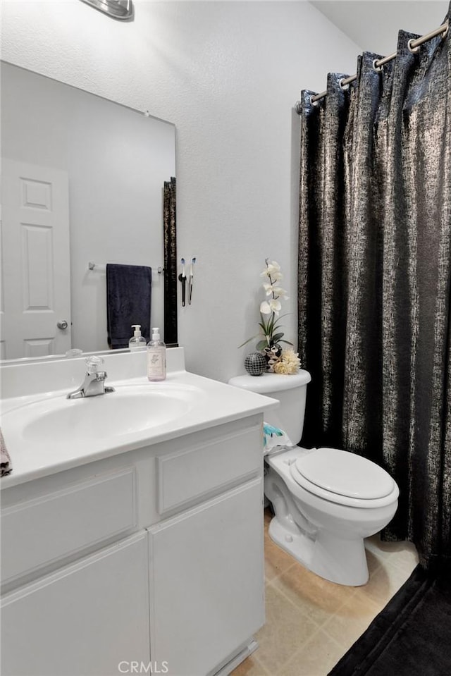 bathroom with tile patterned flooring, vanity, and toilet