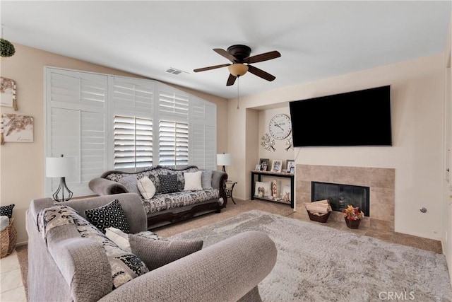 living room featuring a tiled fireplace and ceiling fan