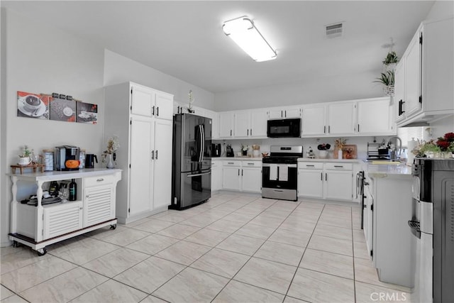 kitchen featuring white cabinetry, sink, light tile patterned floors, and stainless steel appliances