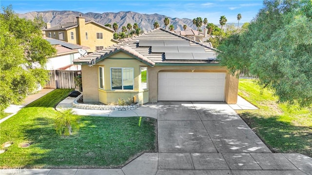 view of front facade featuring solar panels, a garage, a mountain view, and a front lawn