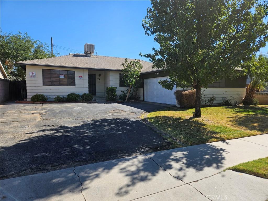 single story home with a front lawn, a garage, and cooling unit