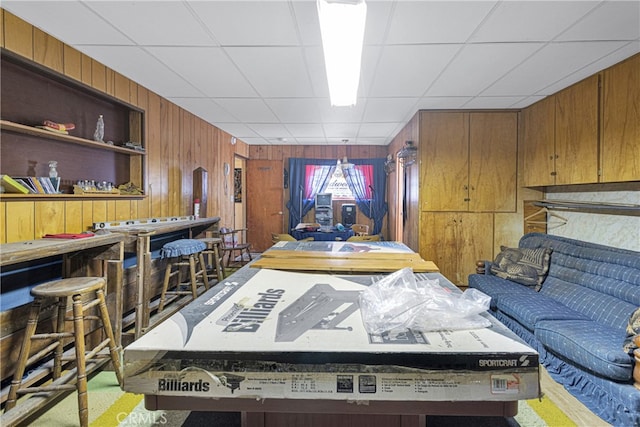 interior space featuring a paneled ceiling, wooden walls, and carpet floors