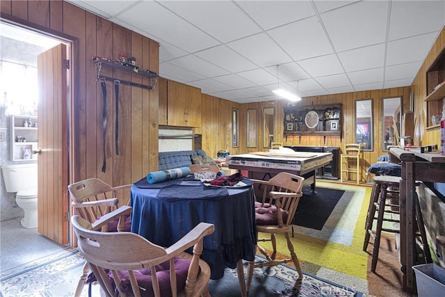 dining space featuring a drop ceiling and wood walls