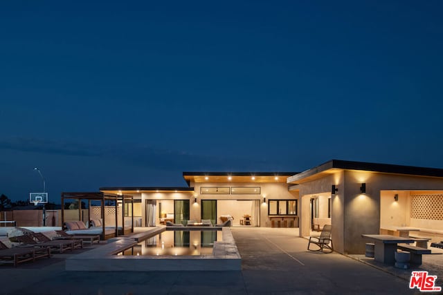 pool at night featuring a patio