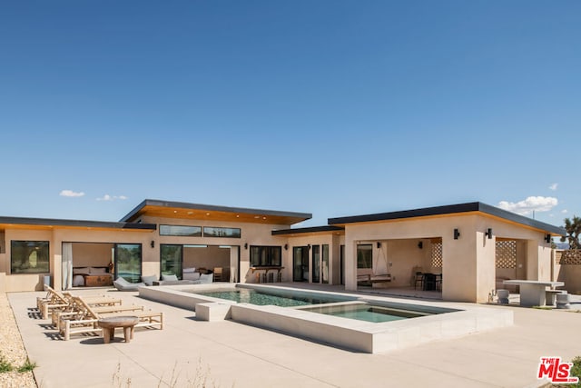 rear view of house featuring a swimming pool with hot tub and a patio area