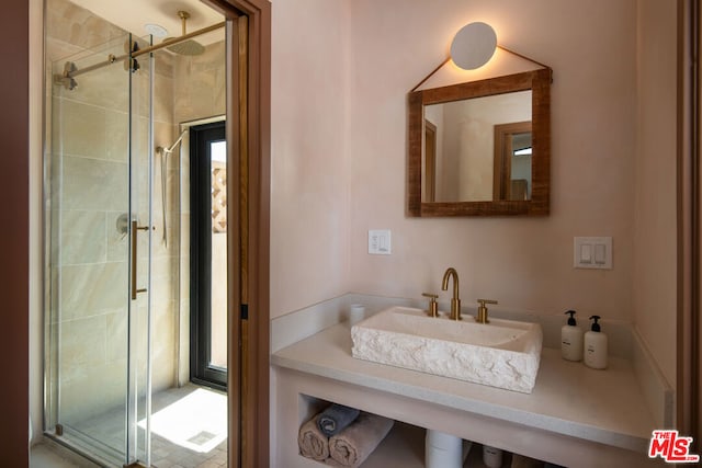 bathroom featuring a shower with door and sink