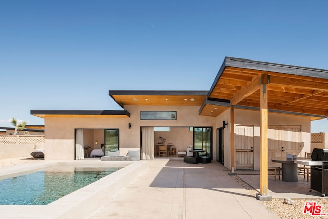 rear view of property with a patio and a fenced in pool