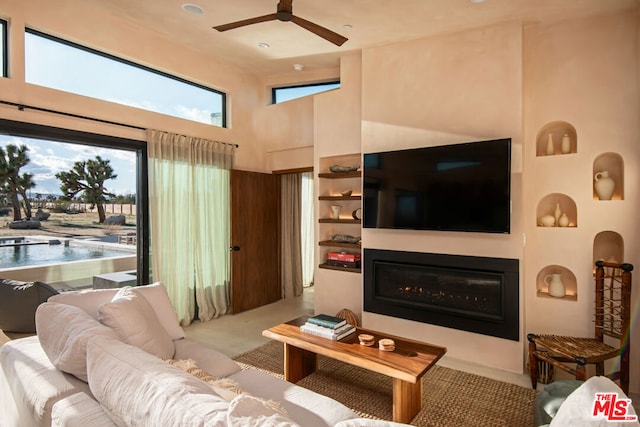 living room with ceiling fan, a towering ceiling, and light colored carpet