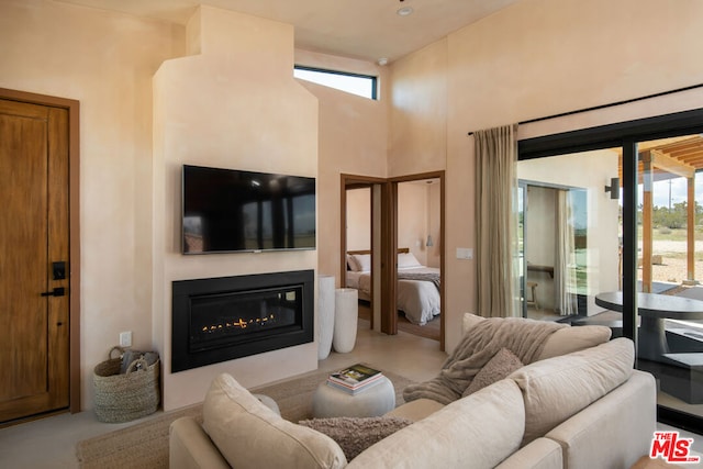 living room with a wealth of natural light, a high ceiling, and concrete flooring