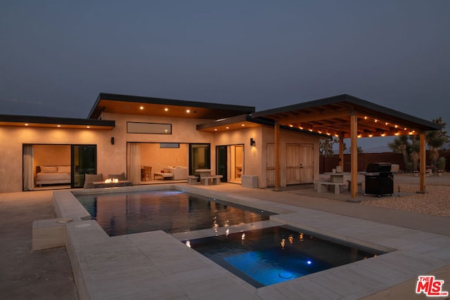 pool at twilight featuring an in ground hot tub, a patio area, and grilling area