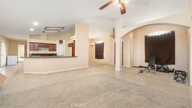 unfurnished living room with lofted ceiling, light tile patterned flooring, and ceiling fan with notable chandelier