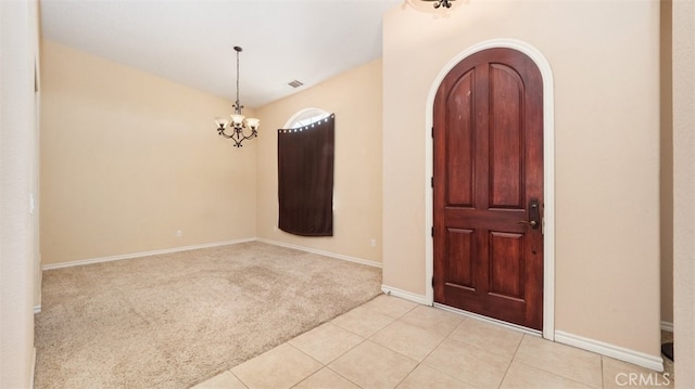 carpeted foyer with an inviting chandelier