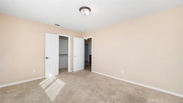 unfurnished bedroom featuring light carpet, a closet, and a textured ceiling