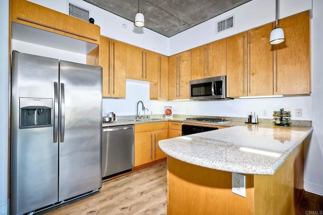 kitchen featuring kitchen peninsula, light hardwood / wood-style flooring, sink, pendant lighting, and stainless steel appliances