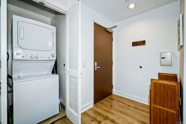 clothes washing area featuring light hardwood / wood-style flooring and stacked washer and clothes dryer