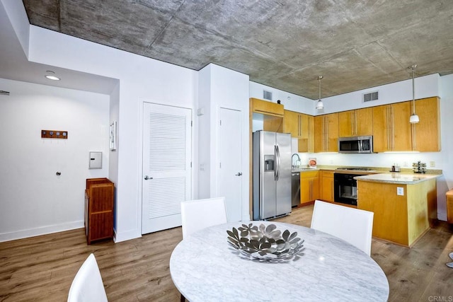 kitchen with light hardwood / wood-style flooring, black appliances, hanging light fixtures, and sink