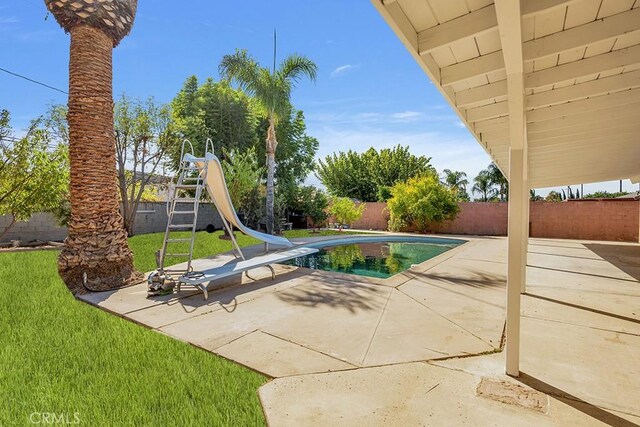 view of pool featuring a lawn, a water slide, and a patio