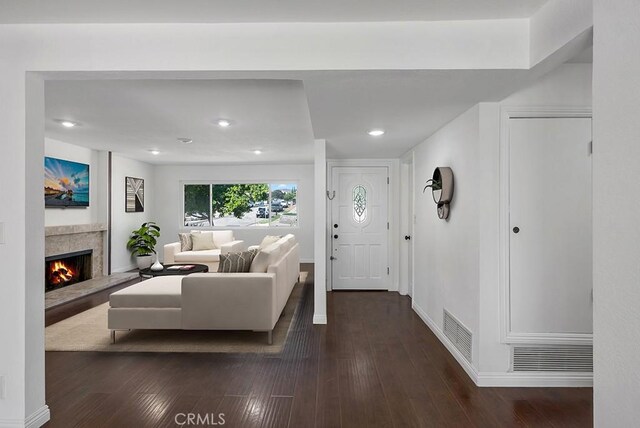 entryway with a high end fireplace and dark wood-type flooring