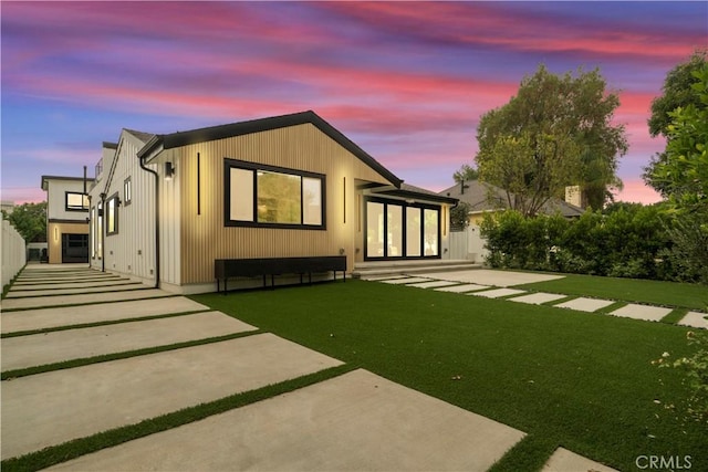 back house at dusk with a lawn