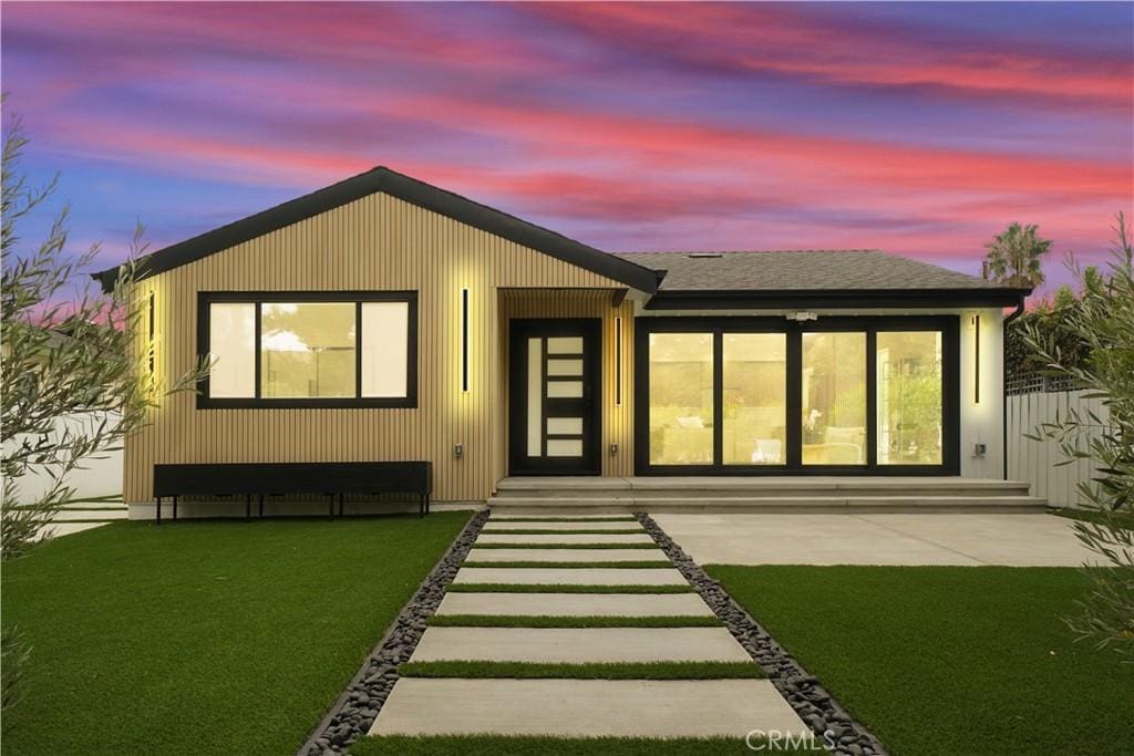 back house at dusk featuring a yard