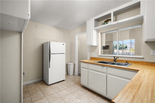 kitchen with a textured ceiling, white cabinetry, sink, and white refrigerator