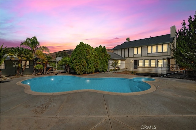 pool at dusk with a patio area