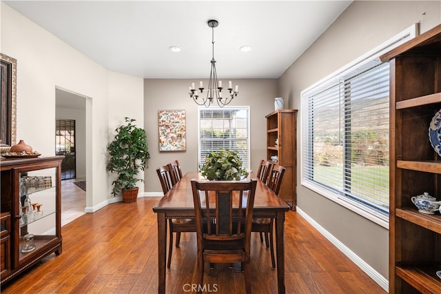 dining area with dark hardwood / wood-style flooring and an inviting chandelier