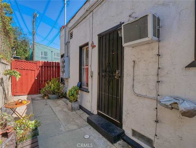 entrance to property with a patio area and a wall mounted air conditioner