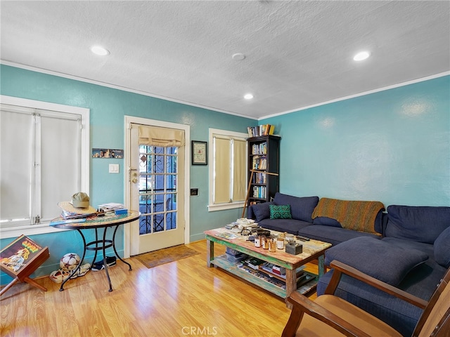 living room featuring ornamental molding, light hardwood / wood-style flooring, and a textured ceiling