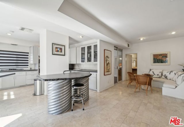 kitchen featuring a breakfast bar area, decorative backsplash, and white cabinetry