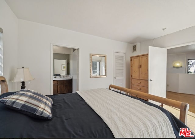 bedroom featuring hardwood / wood-style floors, connected bathroom, and a closet